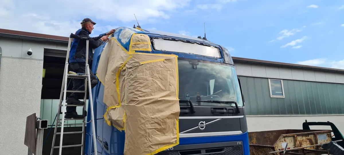 Mitarbeiter beim Abkleben eines LKW-Fahrerhauses für die Lackierung